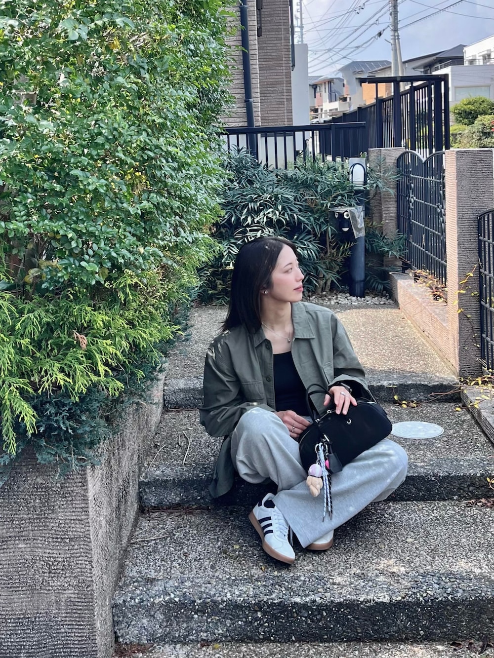 ブラック系のボストンバッグ、ブラック系のキャミソール、グリーン系のミリタリージャケットを着用したレディースの春コーディネートの3枚目の写真