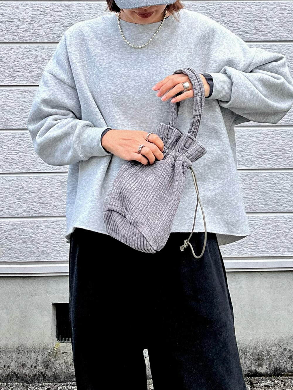 グレー系のハンドバッグ、ブラック系のスウェットパンツ、ブラック系のスニーカーを着用したレディースの秋コーディネートの2枚目の写真