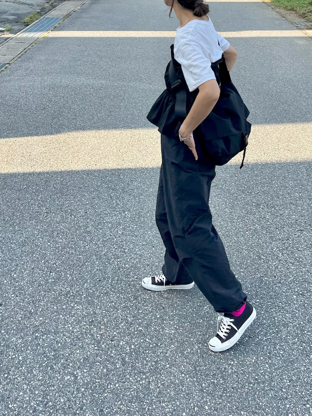 ブラック系のベスト、ブラック系のショルダーバッグ、ホワイト系のTシャツ/カットソーを着用したレディースの秋コーディネートの2枚目の写真