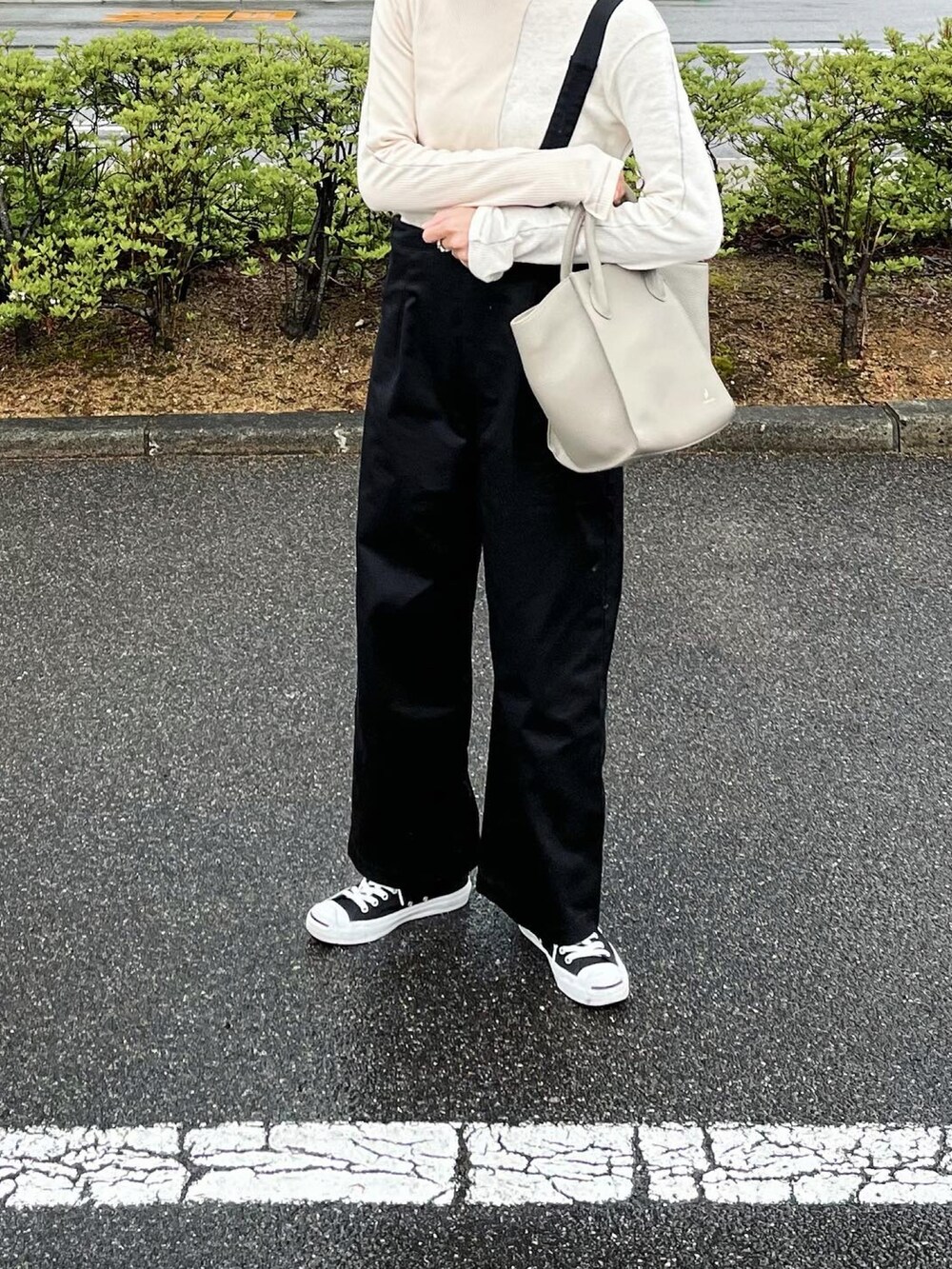 グレー系のバッグ、ホワイト系のTシャツ/カットソー、ブラック系のスニーカーを着用したレディースの春コーディネートの2枚目の写真