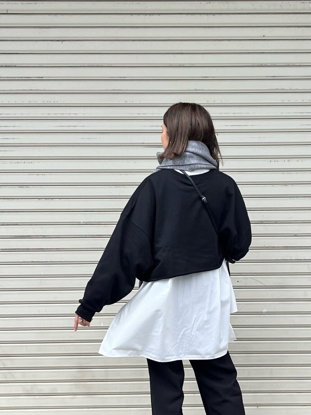 ブラック系のニット/セーター、ホワイト系のシャツ/ブラウス、ブラック系のスラックスを着用したレディースの秋コーディネートの3枚目の写真