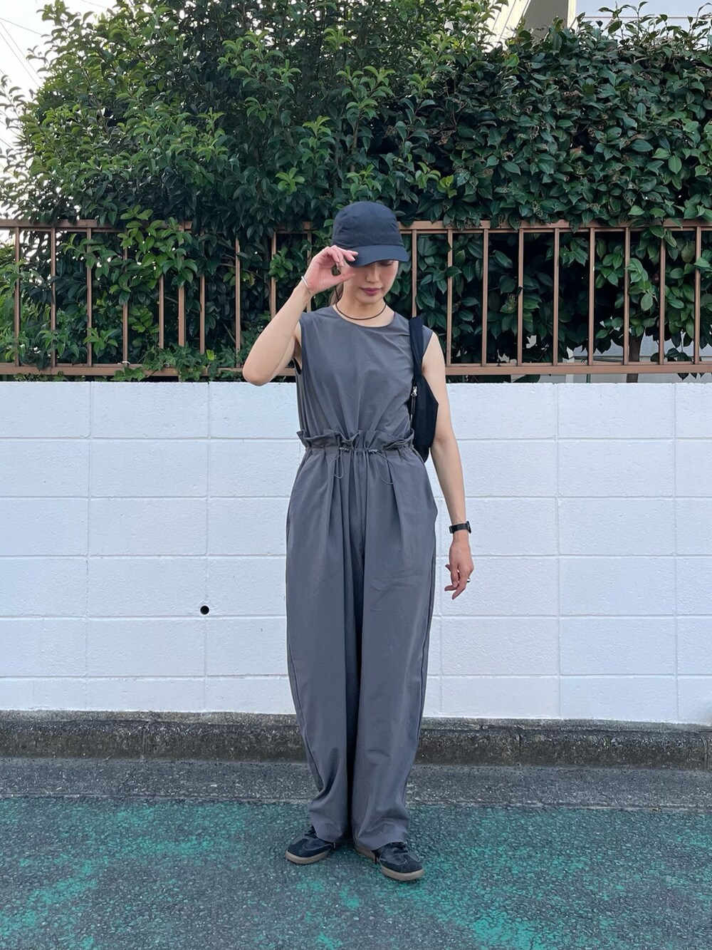 グレー系のつなぎ/オールインワン、ブラック系のスニーカー、ブラック系のキャップを着用したレディースの夏コーディネートの2枚目の写真