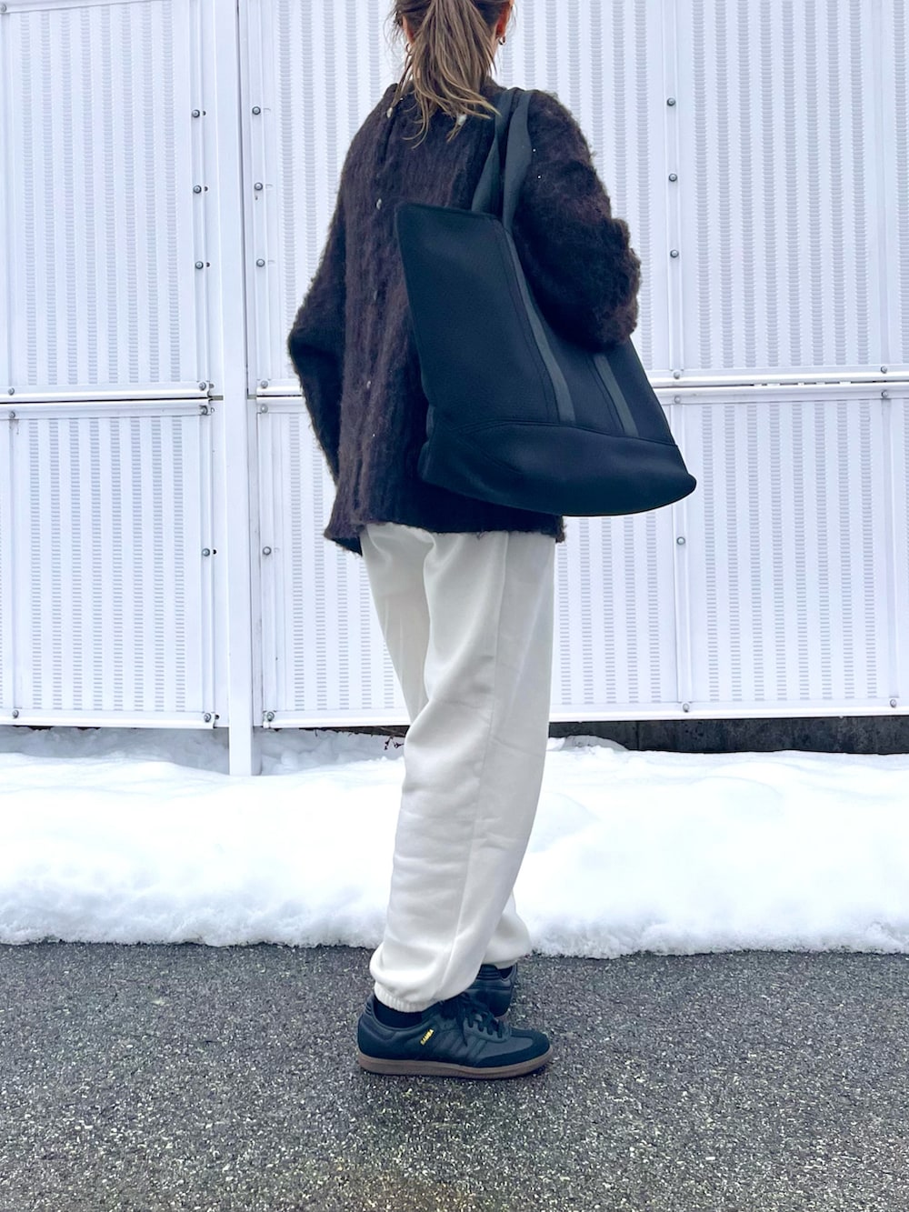 ブラック系のトートバッグ、ブラウン系のカーディガン/ボレロ、ブラック系のスニーカーを着用したレディースの冬コーディネートの3枚目の写真