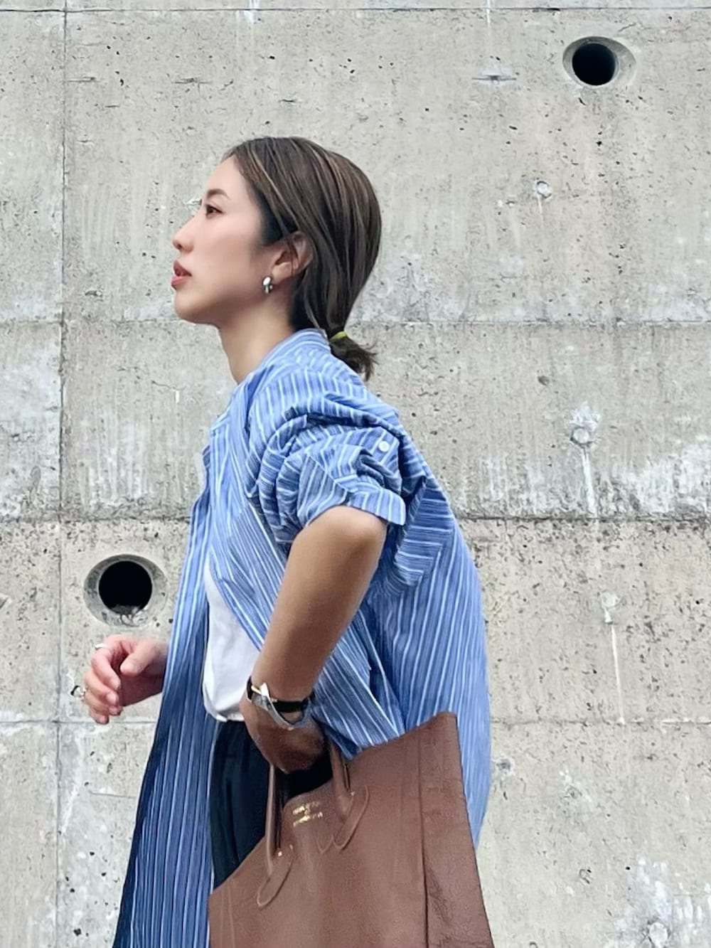 ブルー系のシャツ/ブラウス、ブラウン系のトートバッグ、グレー系のスニーカーを着用したレディースの春コーディネートの2枚目の写真