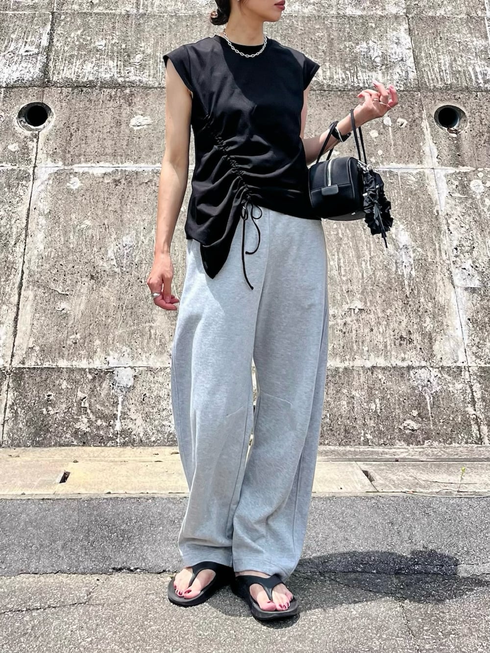 ブラック系のTシャツ/カットソー、グレー系のその他パンツ、ブラック系のサンダルを着用したレディースの夏コーディネートの2枚目の写真