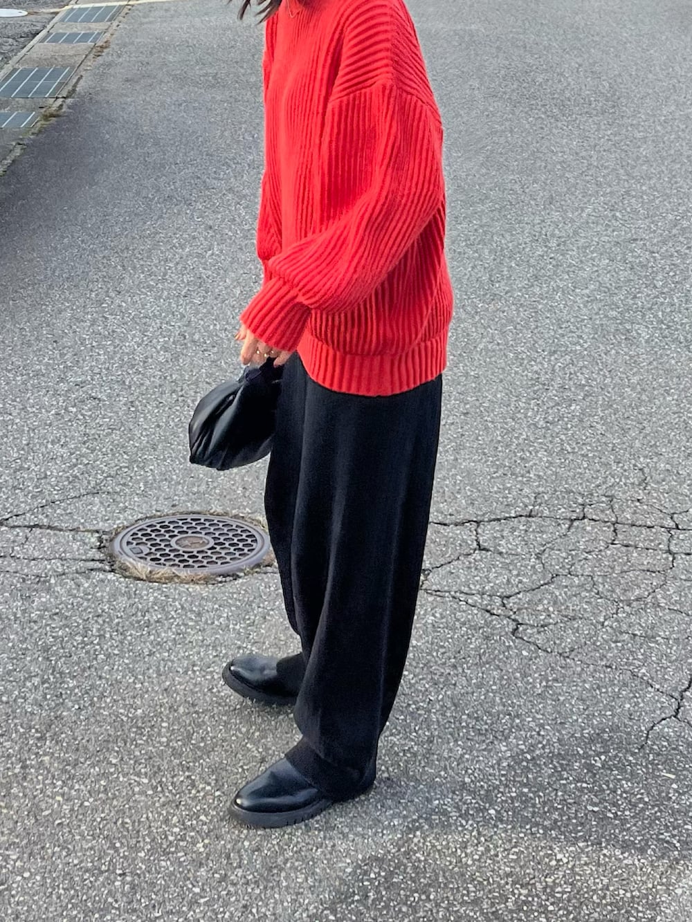 レッド系のニット/セーター、ブラック系のその他パンツ、ブラック系のブーツを着用したレディースの秋コーディネートの2枚目の写真