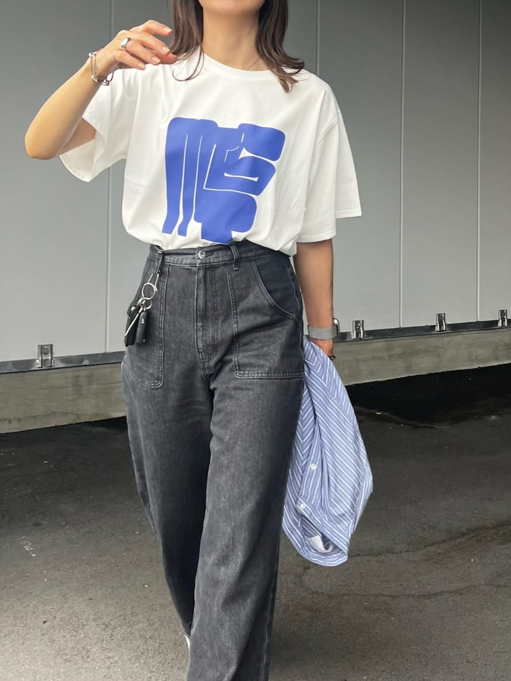 グレー系のデニムパンツ、ブラック系のボストンバッグ、ホワイト系のTシャツ/カットソーを着用したレディースの春コーディネートの2枚目の写真