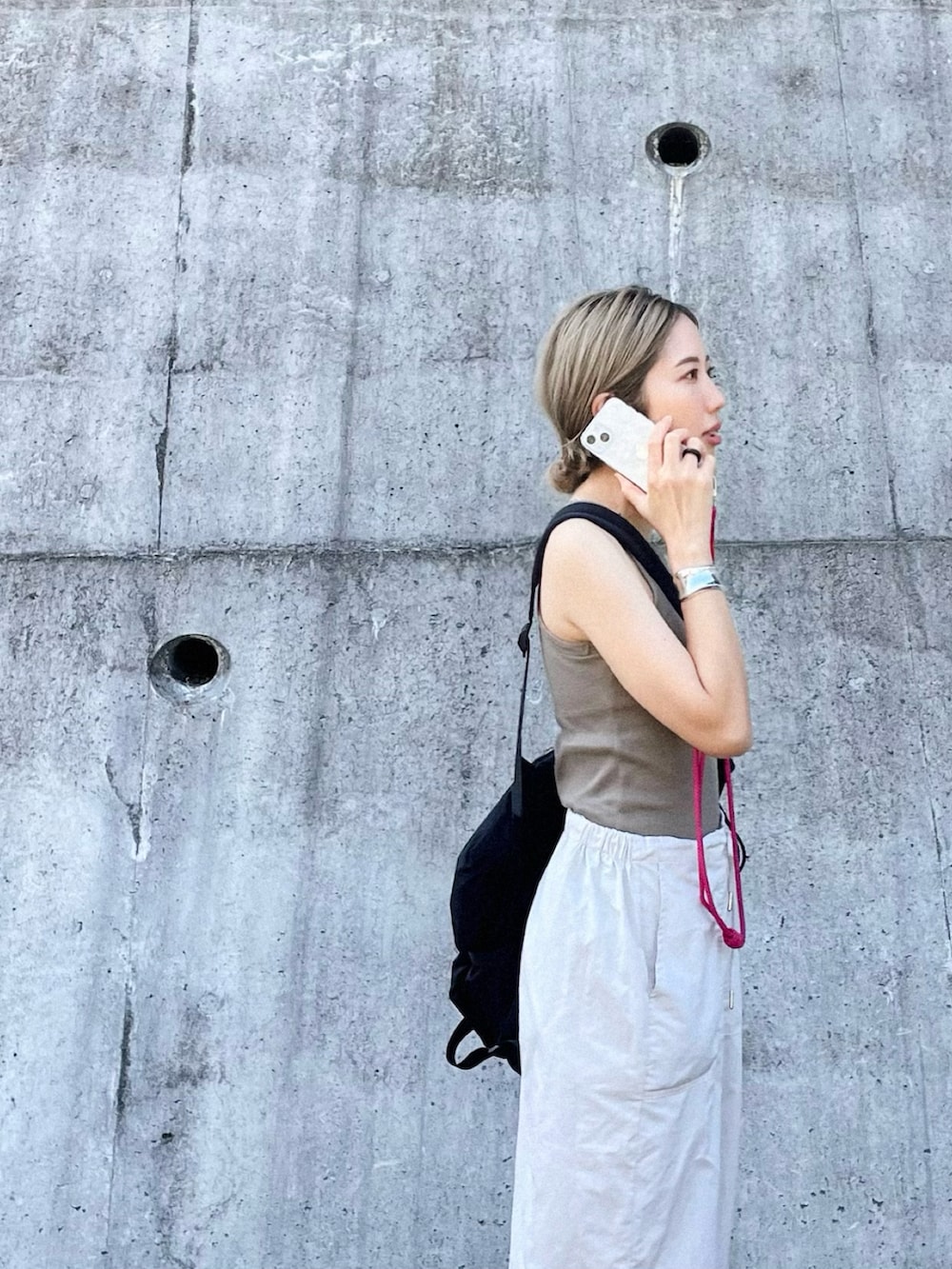 グリーン系のタンクトップ、ホワイト系のカーゴパンツ、ブラック系のサンダルを着用したレディースの夏コーディネートの2枚目の写真