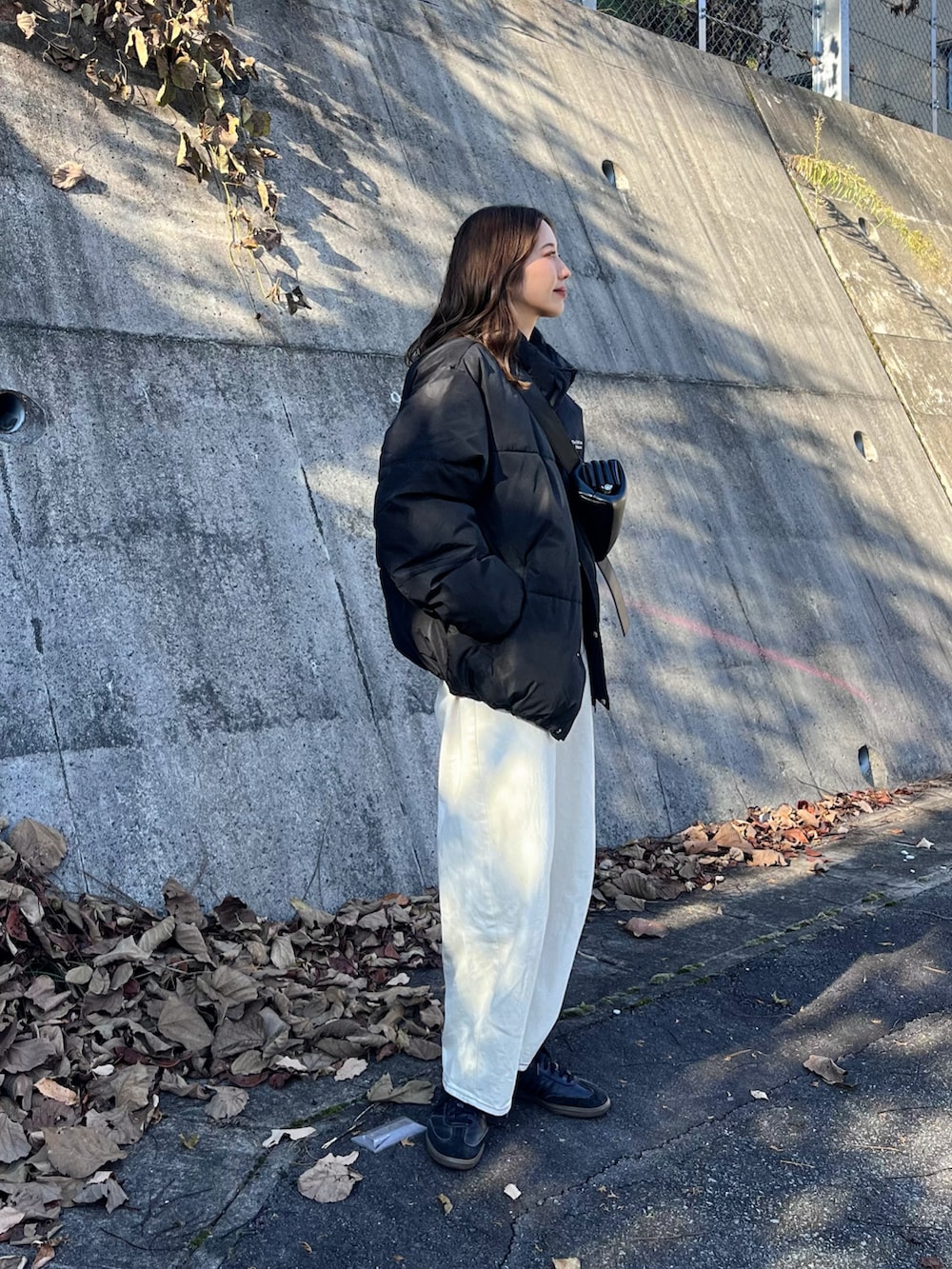 ブラック系のダウンジャケット/コート、ホワイト系のデニムパンツ、ブラック系のスニーカーを着用したレディースの秋コーディネートの2枚目の写真