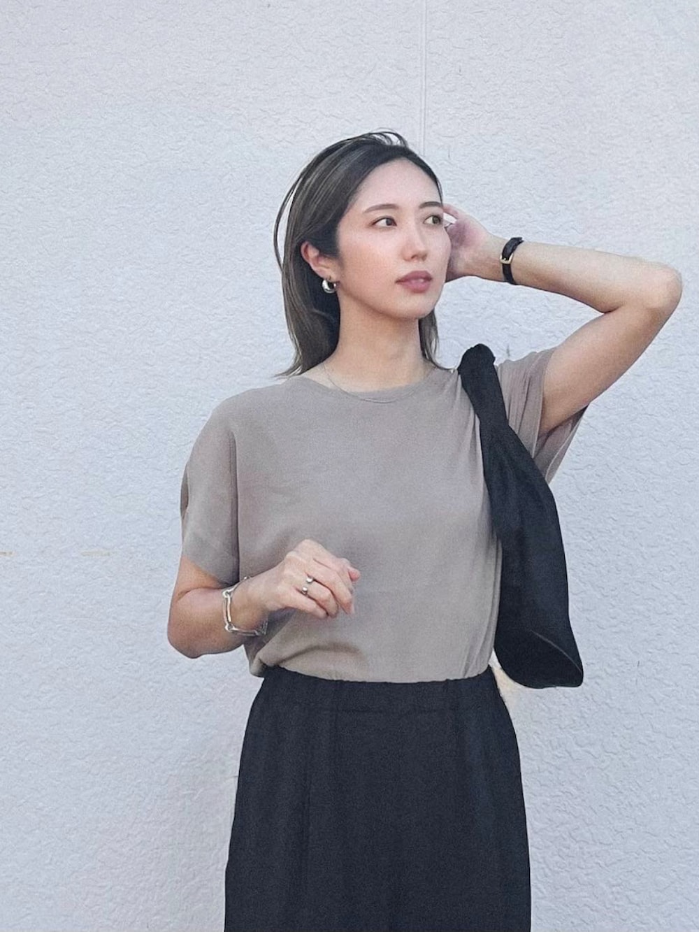 ベージュ系のニット/セーター、ブラック系のハンドバッグ、ブラック系のサンダルを着用したレディースの夏コーディネートの2枚目の写真