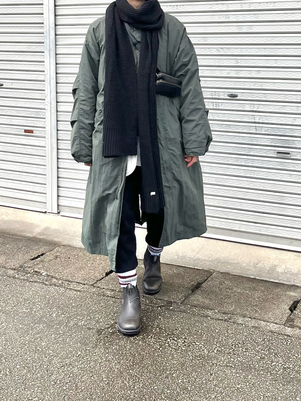 グリーン系のミリタリージャケット、ブラック系のボディバッグ/ウエストポーチ、ブラック系のブーツを着用したレディースの冬コーディネートの2枚目の写真