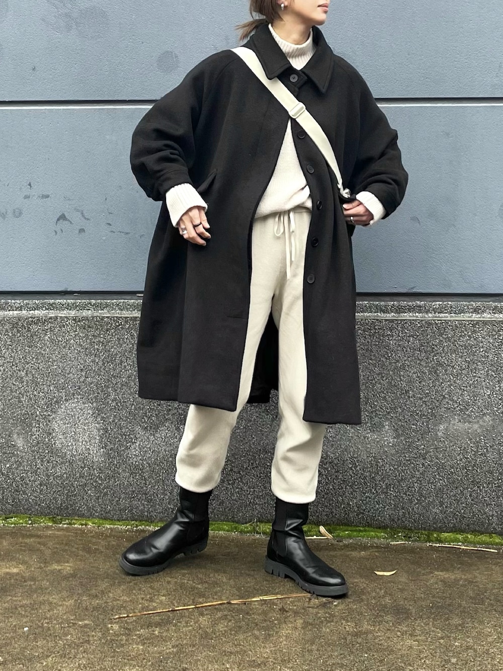 ブラック系のジャケット/アウター、ホワイト系のショルダーバッグ、ブラック系のブーツを着用したレディースの冬コーディネートの2枚目の写真