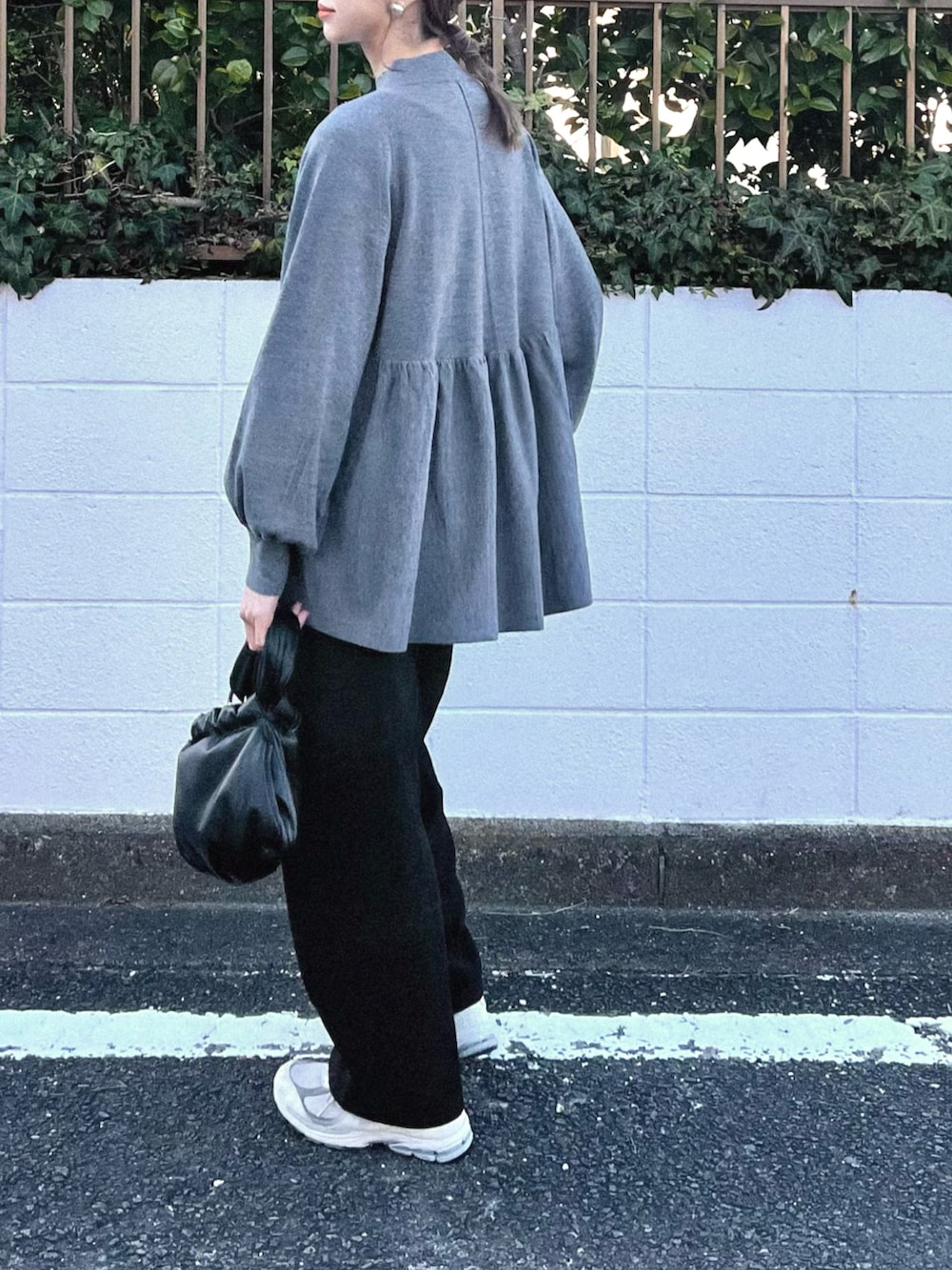 グレー系のニット/セーター、ブラック系のその他パンツ、シルバー系のイヤリングを着用したレディースの冬コーディネートの2枚目の写真