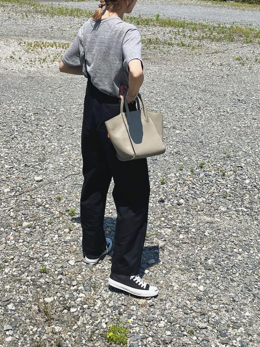 グレー系のバッグ、グレー系のTシャツ/カットソー、ブラック系のスニーカーを着用したレディースの春コーディネートの2枚目の写真