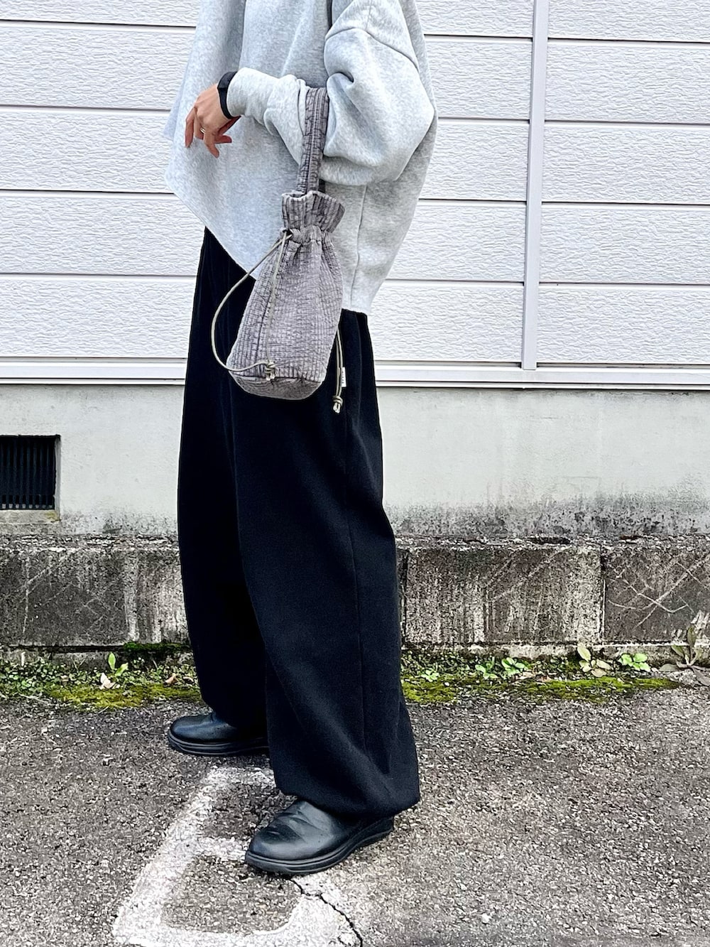 グレー系のハンドバッグ、ブラック系のスウェットパンツ、ブラック系のスニーカーを着用したレディースの秋コーディネートの3枚目の写真