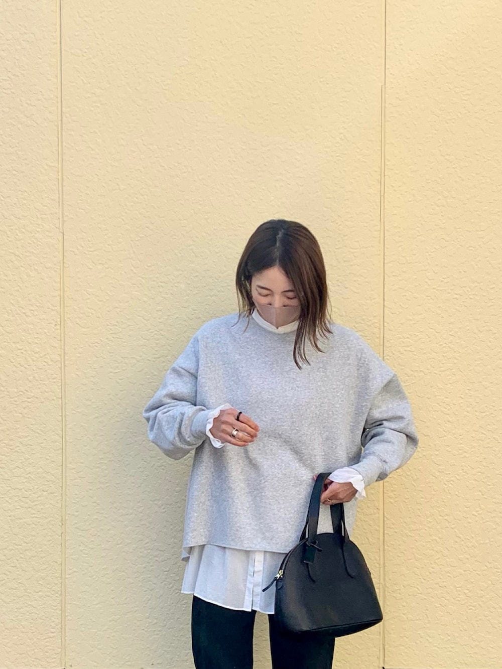 グレー系のスウェット、ホワイト系のシャツ/ブラウス、ブラック系のデニムパンツを着用したレディースの秋コーディネートの2枚目の写真