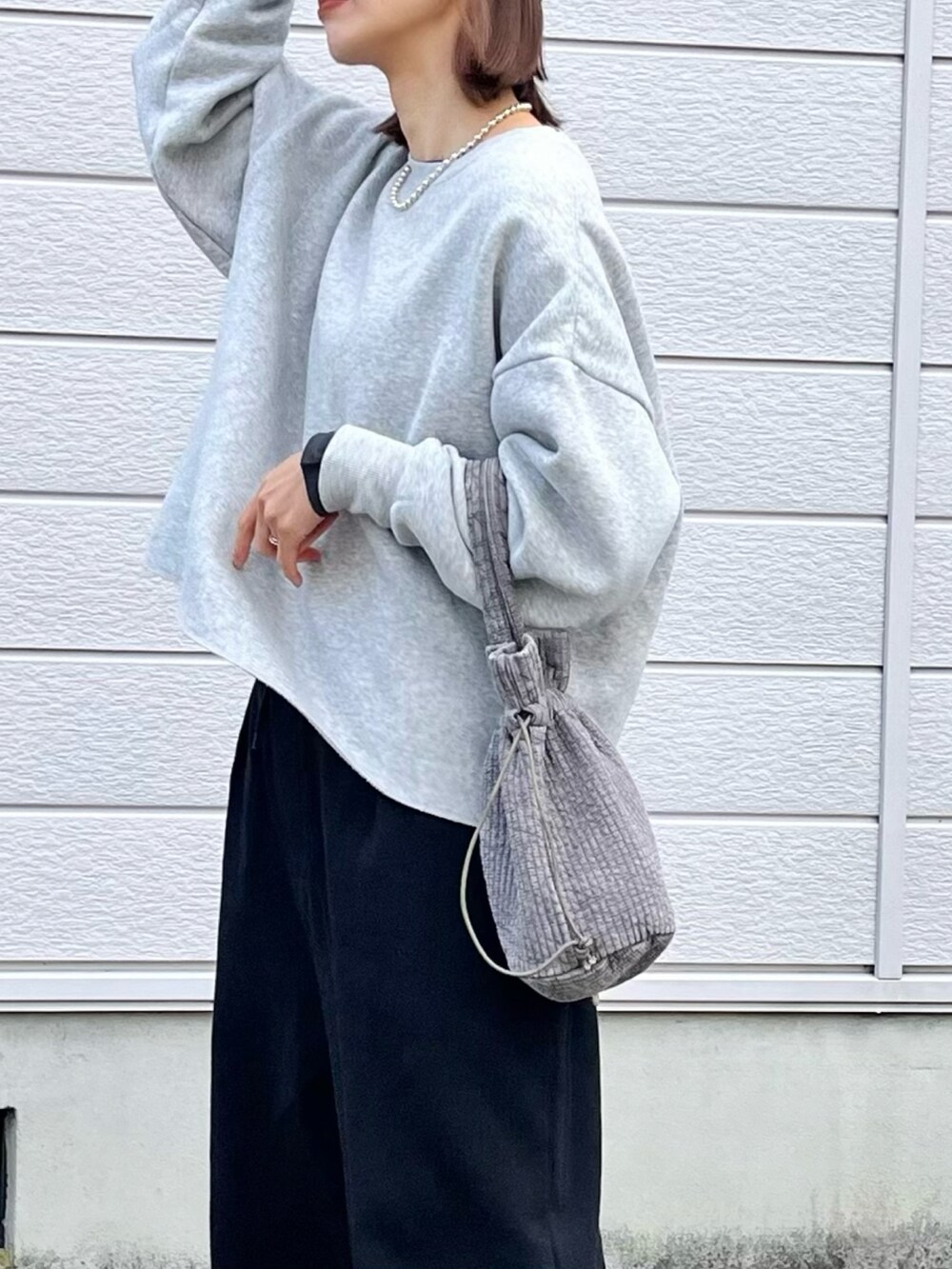 グレー系のハンドバッグ、ブラック系のスウェットパンツ、ブラック系のスニーカーを着用したレディースの秋コーディネートの4枚目の写真