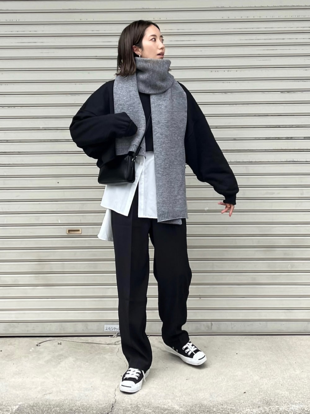 ブラック系のニット/セーター、ホワイト系のシャツ/ブラウス、ブラック系のスラックスを着用したレディースの秋コーディネートの2枚目の写真