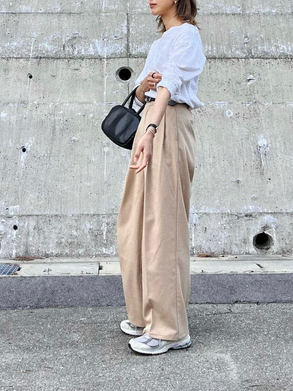 ベージュ系のスラックス、ホワイト系のTシャツ/カットソー、ブラック系のボストンバッグを着用したレディースの春コーディネートの2枚目の写真