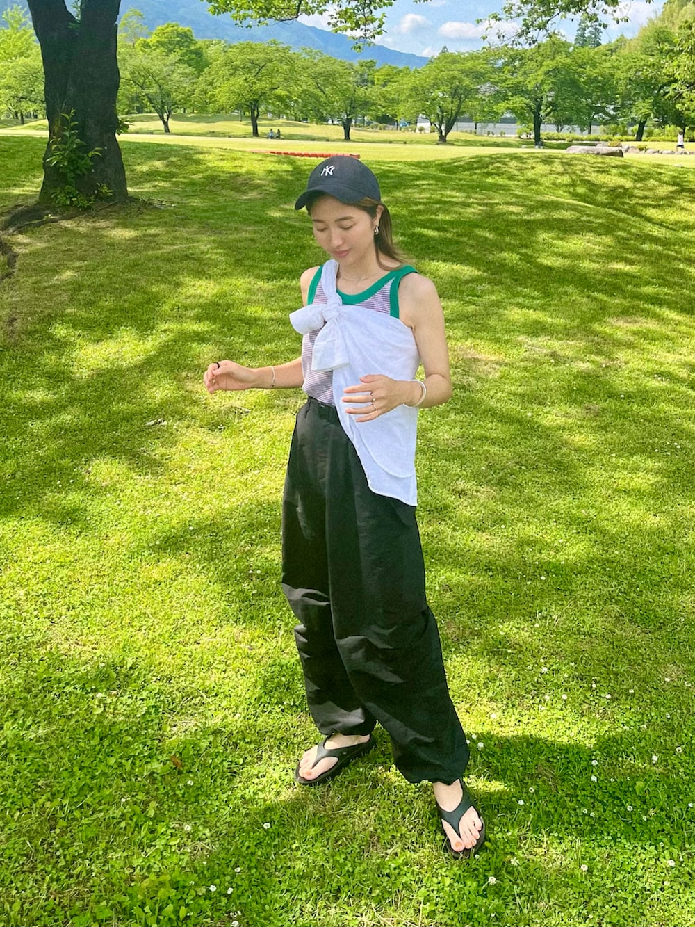 ブラック系のカーゴパンツ、ブラック系のサンダル、ホワイト系のシャツ/ブラウスを着用したレディースの春コーディネートの2枚目の写真