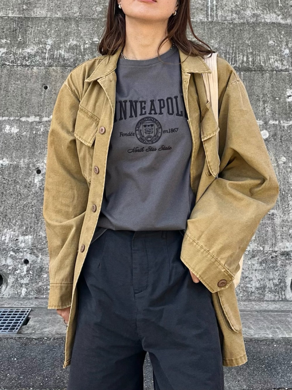 イエロー系のミリタリージャケット、ブラック系のショルダーバッグ、ホワイト系のデニムパンツを着用したレディースの春コーディネートの5枚目の写真