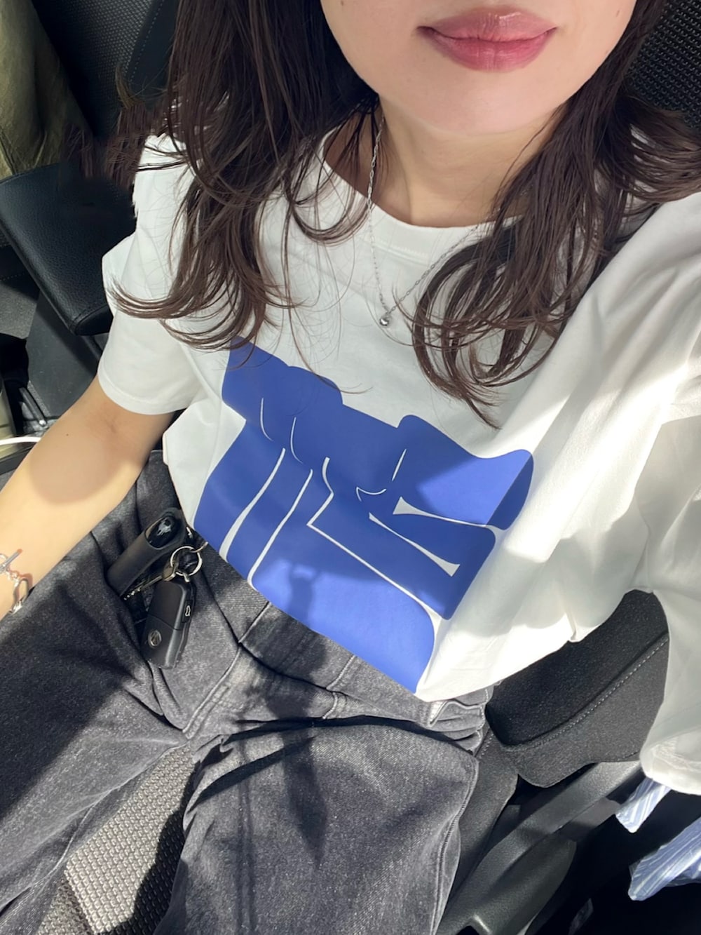 グレー系のデニムパンツ、ブラック系のボストンバッグ、ホワイト系のTシャツ/カットソーを着用したレディースの春コーディネートの3枚目の写真