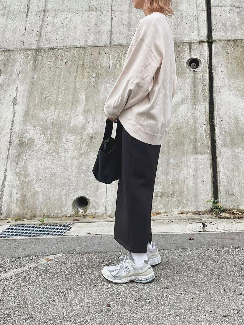 ブラック系のスカート、ブラック系のトートバッグ、グレー系のスニーカーを着用したレディースの秋コーディネートの2枚目の写真