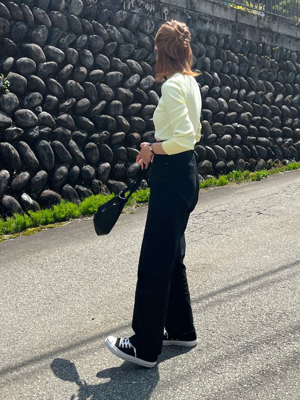 イエロー系のTシャツ/カットソー、ブラック系のデニムパンツ、ブラック系のスニーカーを着用したレディースの春コーディネートの2枚目の写真