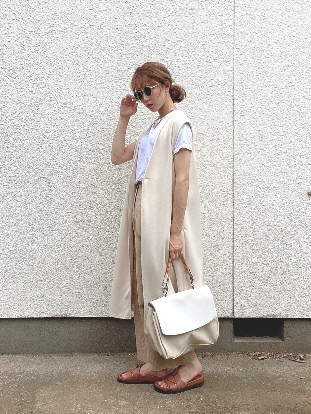 ベージュ系のパンツ、ホワイト系のTシャツ/カットソー、ブラウン系のサンダルを着用したレディースの夏コーディネートの2枚目の写真