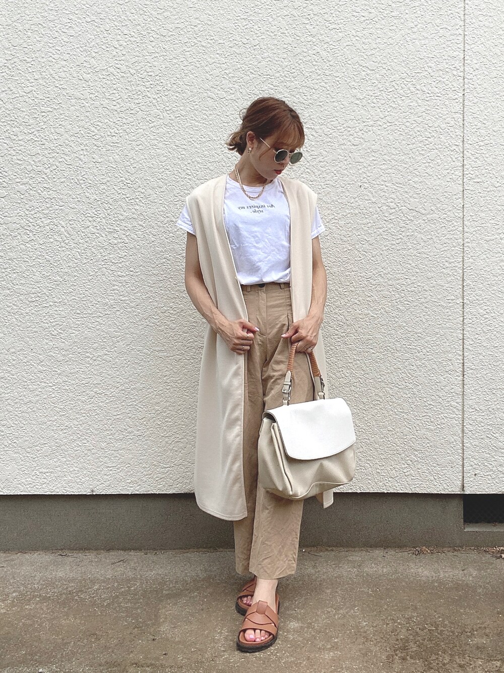 ベージュ系のパンツ、ホワイト系のTシャツ/カットソー、ブラウン系のサンダルを着用したレディースの夏コーディネートの3枚目の写真
