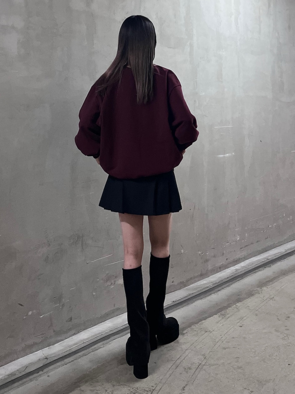 レッド系のスウェット、ブラック系のスカート、ブラック系のブーツを着用したレディースの冬コーディネートの3枚目の写真