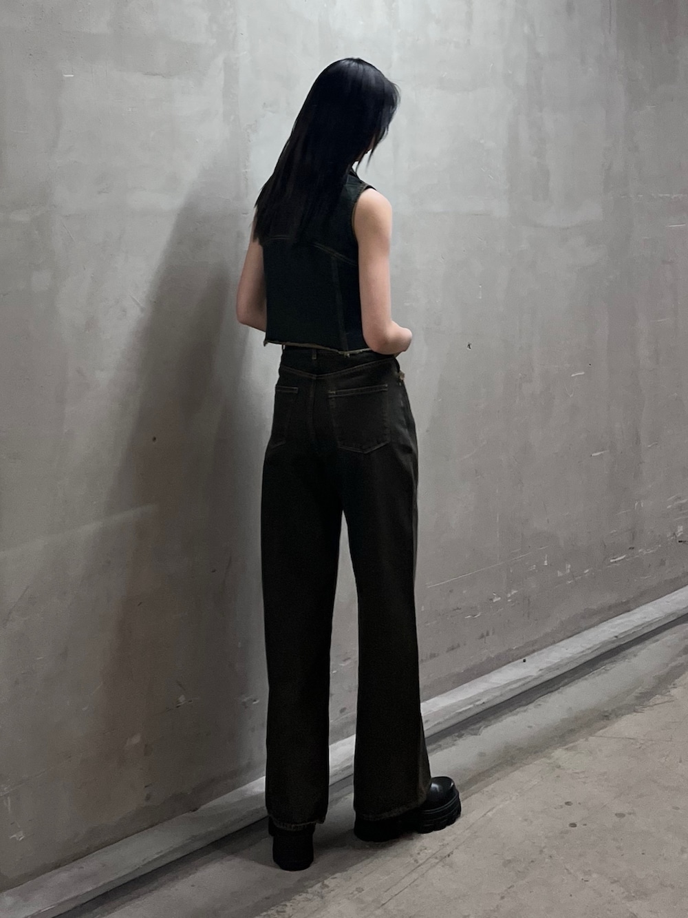 ブルー系のベスト、ブルー系のデニムパンツ、ブラック系のブーツを着用したレディースの春コーディネートの3枚目の写真