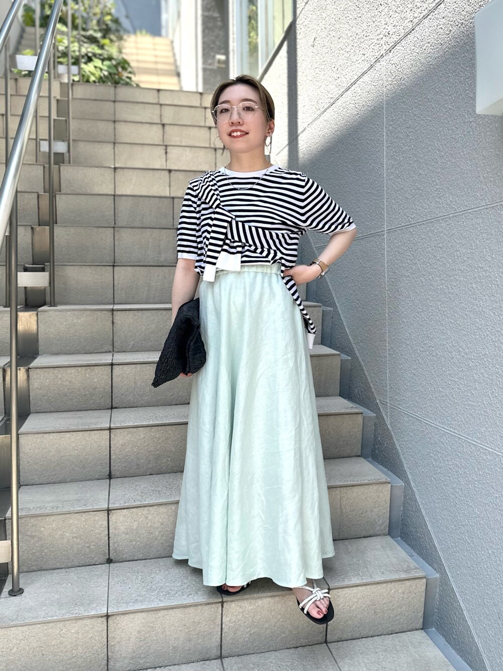 グリーン系のスカート、ブラック系のニット/セーター、ブラック系のカーディガン/ボレロを着用したレディースの夏コーディネートの6枚目の写真