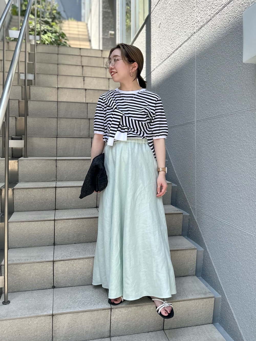 グリーン系のスカート、ブラック系のニット/セーター、ブラック系のカーディガン/ボレロを着用したレディースの夏コーディネートの4枚目の写真