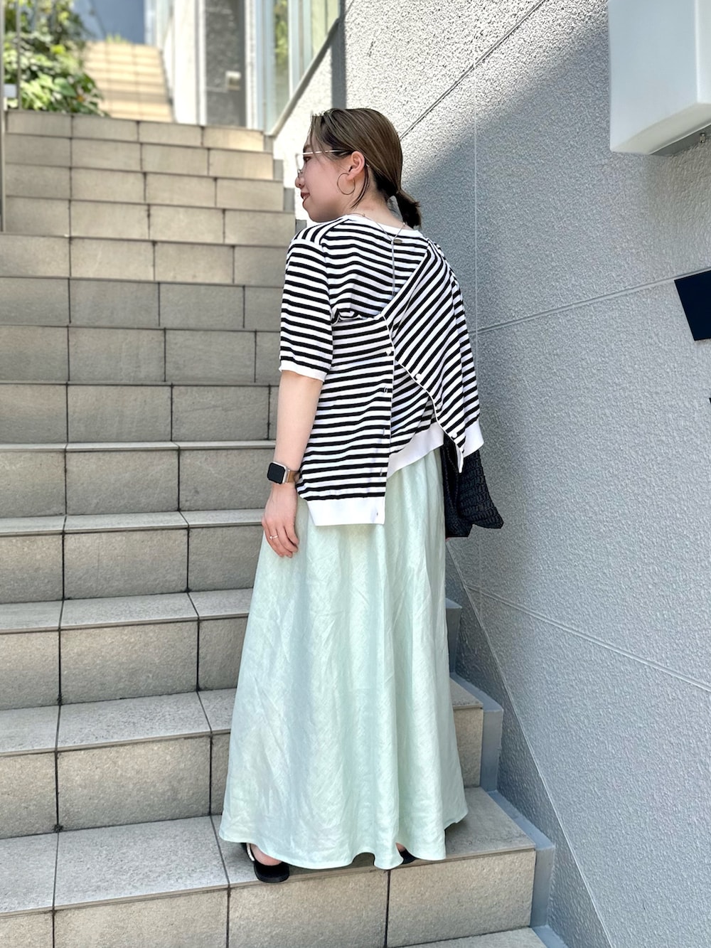 グリーン系のスカート、ブラック系のニット/セーター、ブラック系のカーディガン/ボレロを着用したレディースの夏コーディネートの5枚目の写真