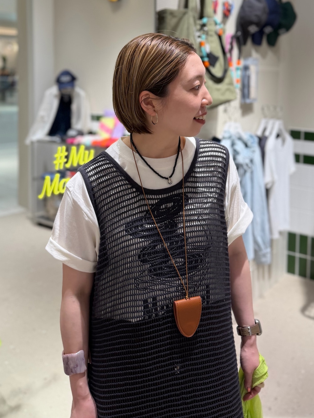 ホワイト系のTシャツ/カットソー、グレー系のニット/セーター、ブラウン系のスカートを着用したレディースの春コーディネートの6枚目の写真