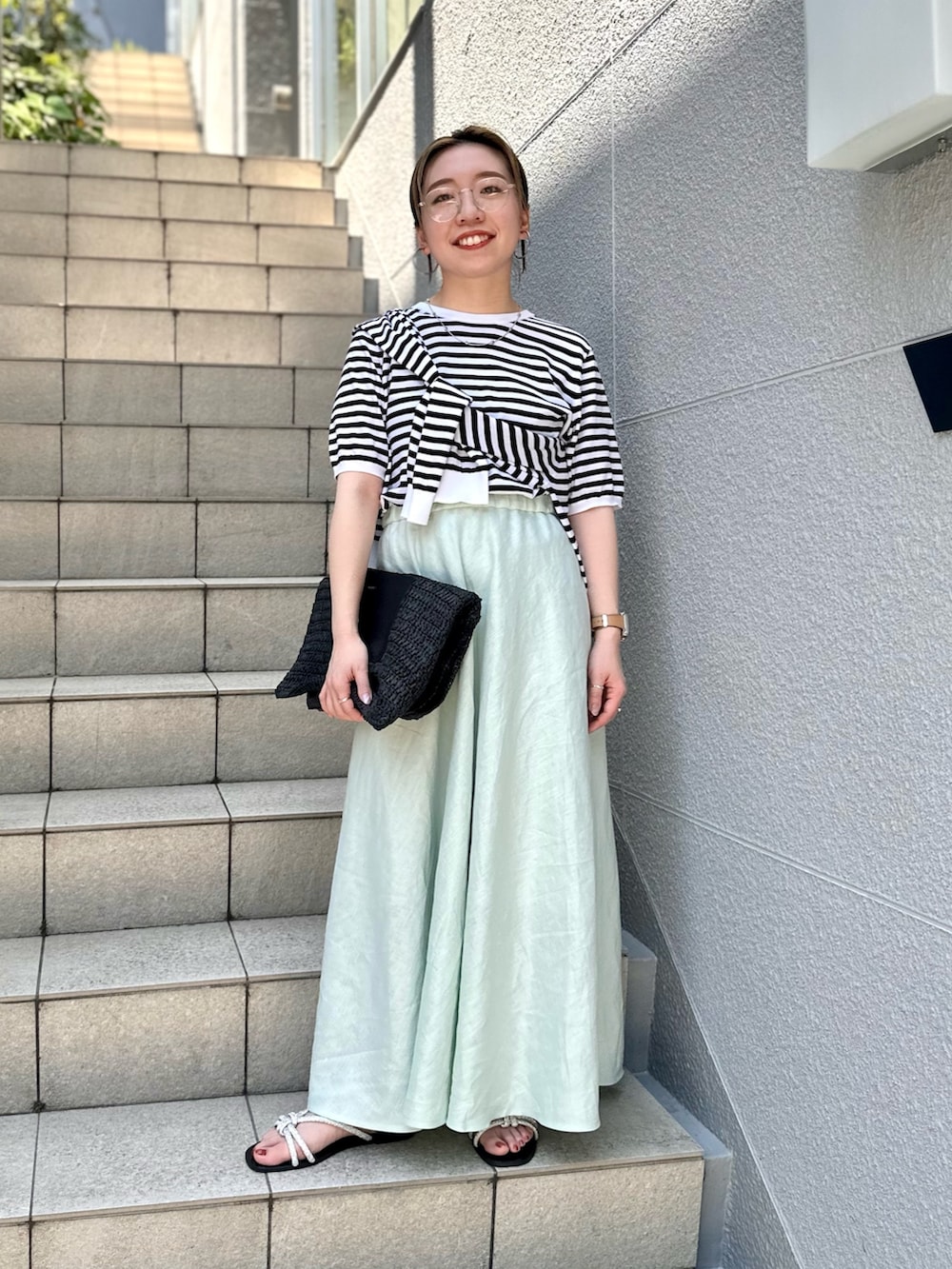 グリーン系のスカート、ブラック系のニット/セーター、ブラック系のカーディガン/ボレロを着用したレディースの夏コーディネートの2枚目の写真