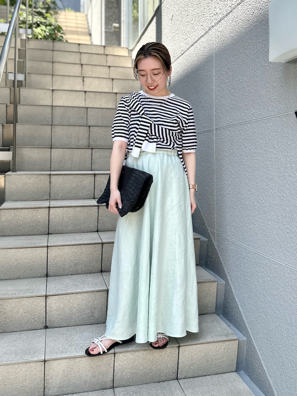 グリーン系のスカート、ブラック系のニット/セーター、ブラック系のカーディガン/ボレロを着用したレディースの夏コーディネートの3枚目の写真