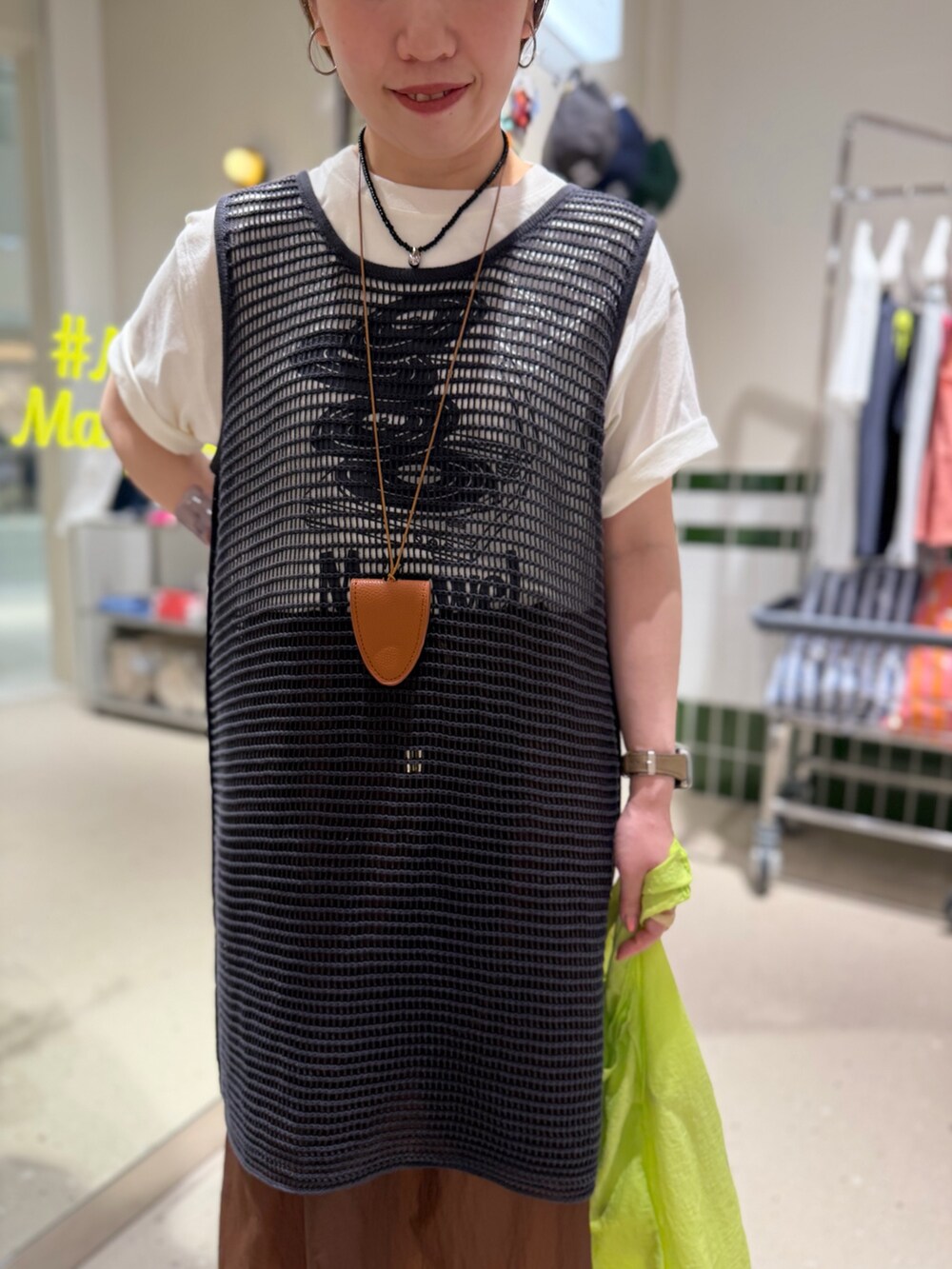 ホワイト系のTシャツ/カットソー、グレー系のニット/セーター、ブラウン系のスカートを着用したレディースの春コーディネートの5枚目の写真