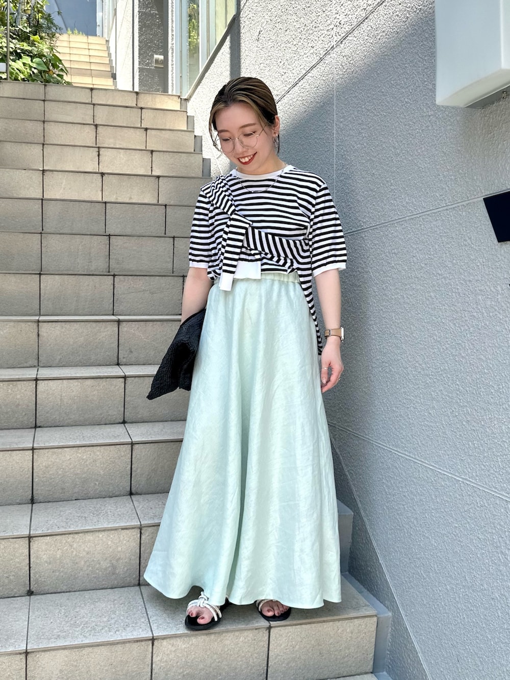 グリーン系のスカート、ブラック系のニット/セーター、ブラック系のカーディガン/ボレロを着用したレディースの夏コーディネートの7枚目の写真