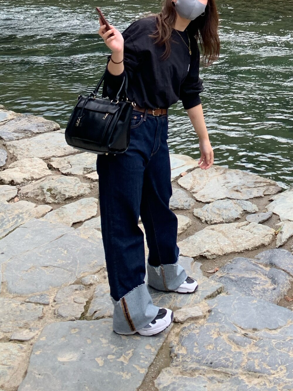 ブルー系のデニムパンツ、ブラック系のTシャツ/カットソー、ホワイト系のスニーカーを着用したレディースの冬コーディネートの2枚目の写真