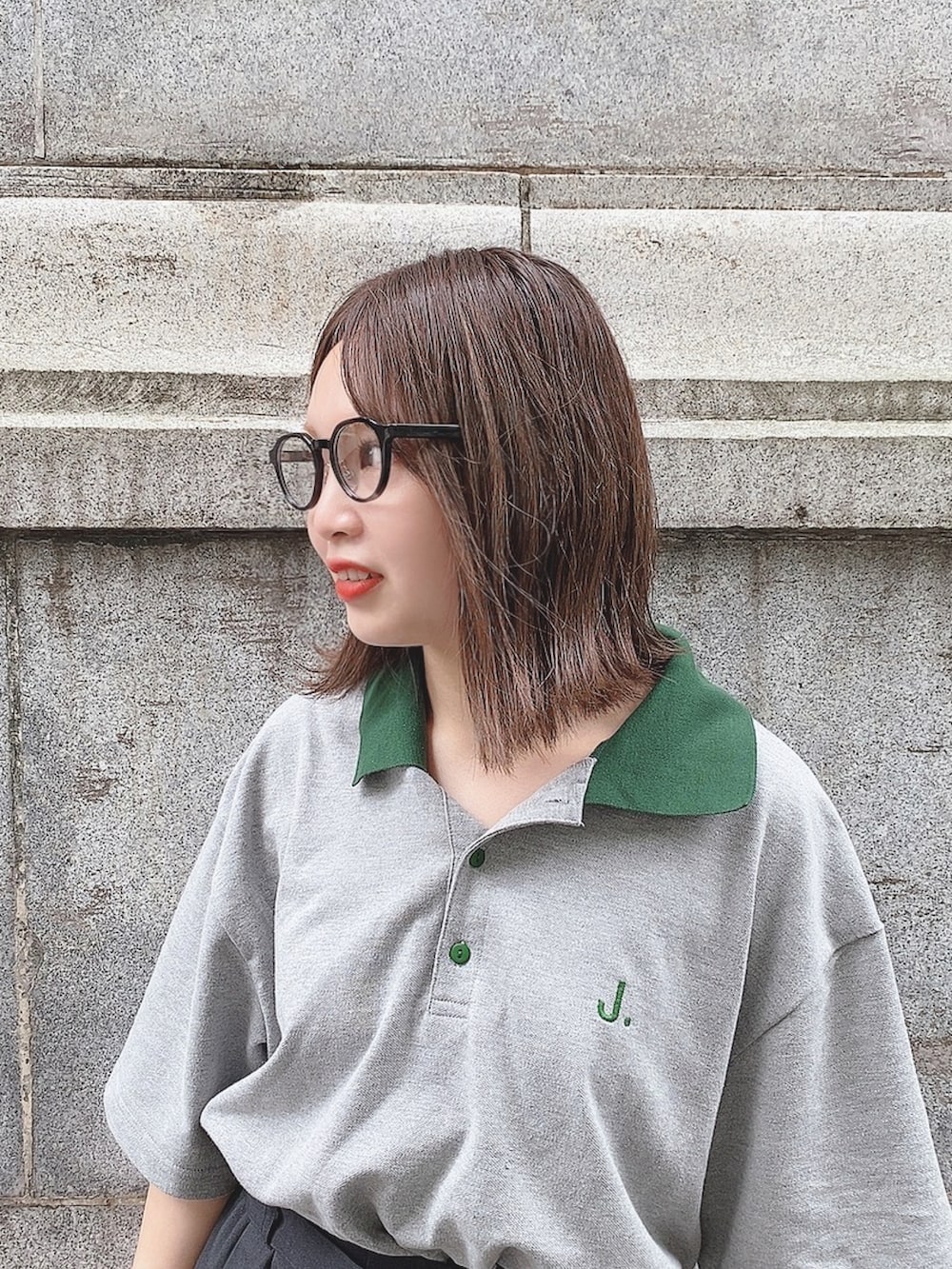 グレー系のポロシャツ、ブラック系のパンツ、ホワイト系のスニーカーを着用したレディースの冬コーディネートの2枚目の写真