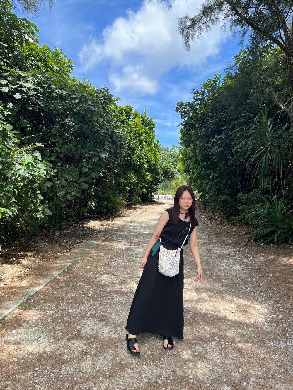 ブラック系のワンピース、ブラック系のサンダル、ベージュ系の帽子を着用したレディースの夏コーディネートの2枚目の写真