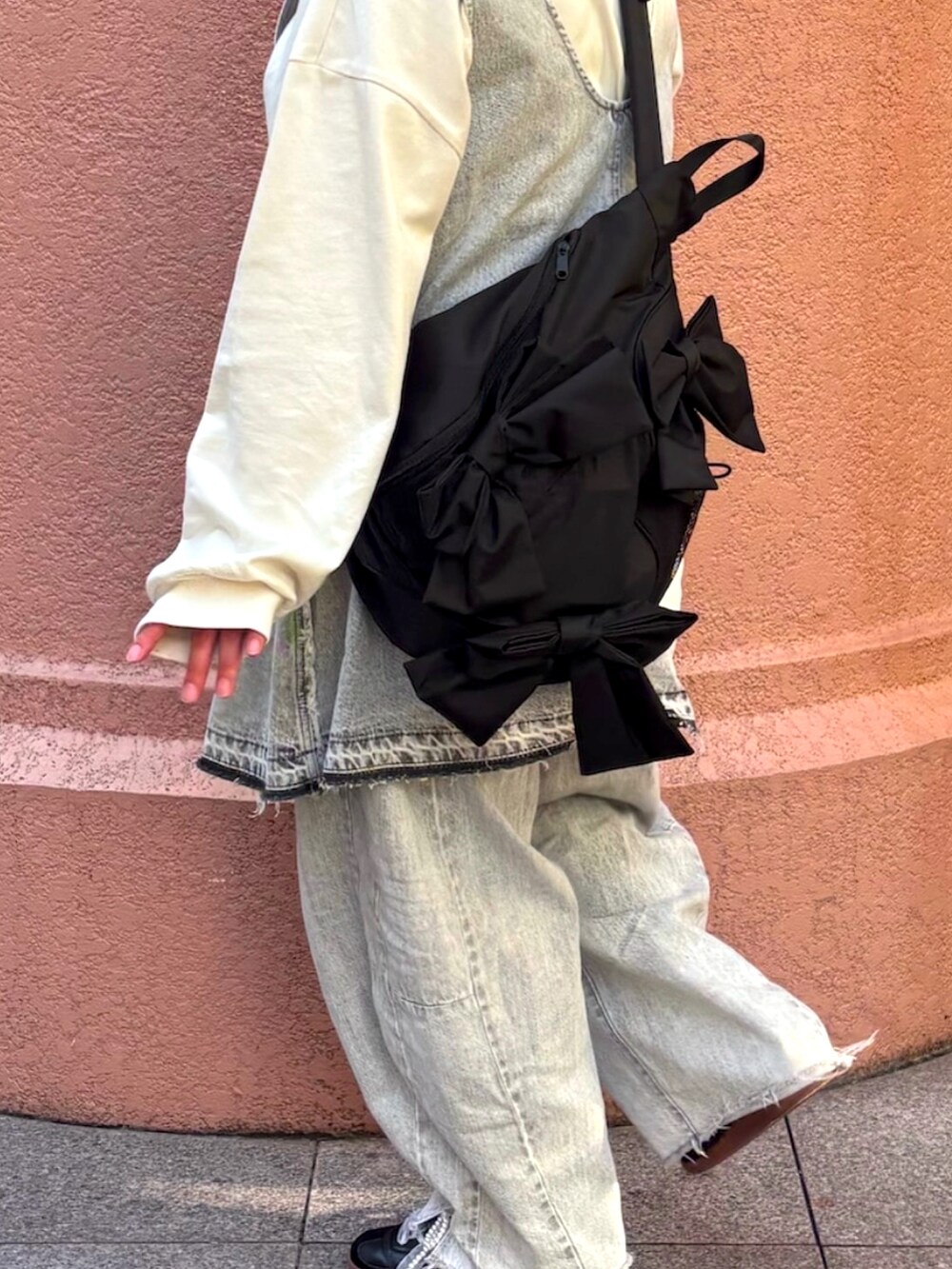グレー系のドレス、ブラック系のショルダーバッグ、グレー系のデニムパンツを着用したレディースの春コーディネートの2枚目の写真