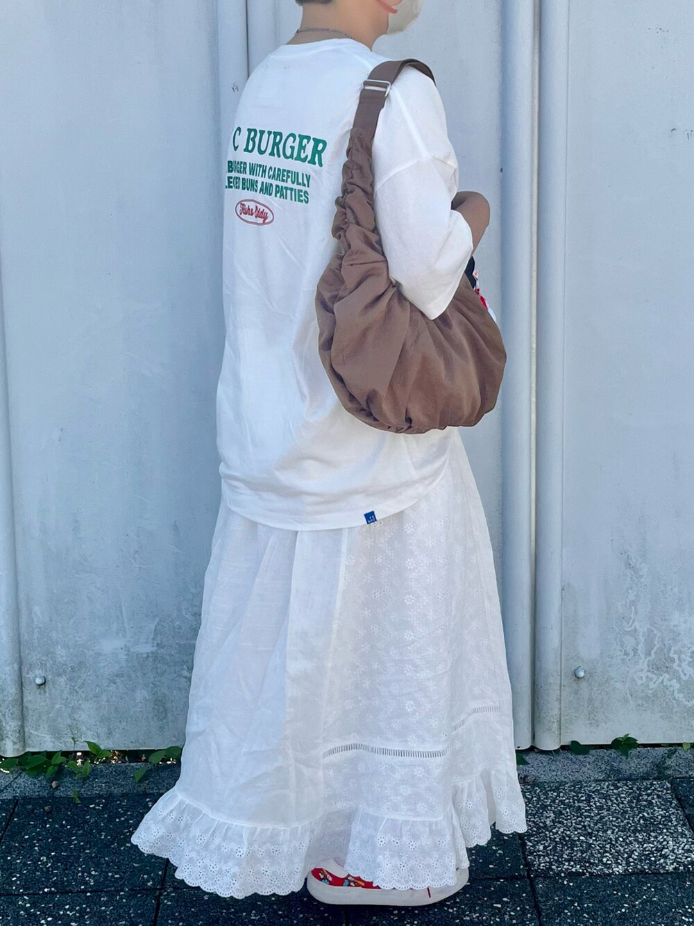 ホワイト系のTシャツ/カットソー、ホワイト系のスカート、レッド系のスニーカーを着用したレディースの秋コーディネートの2枚目の写真