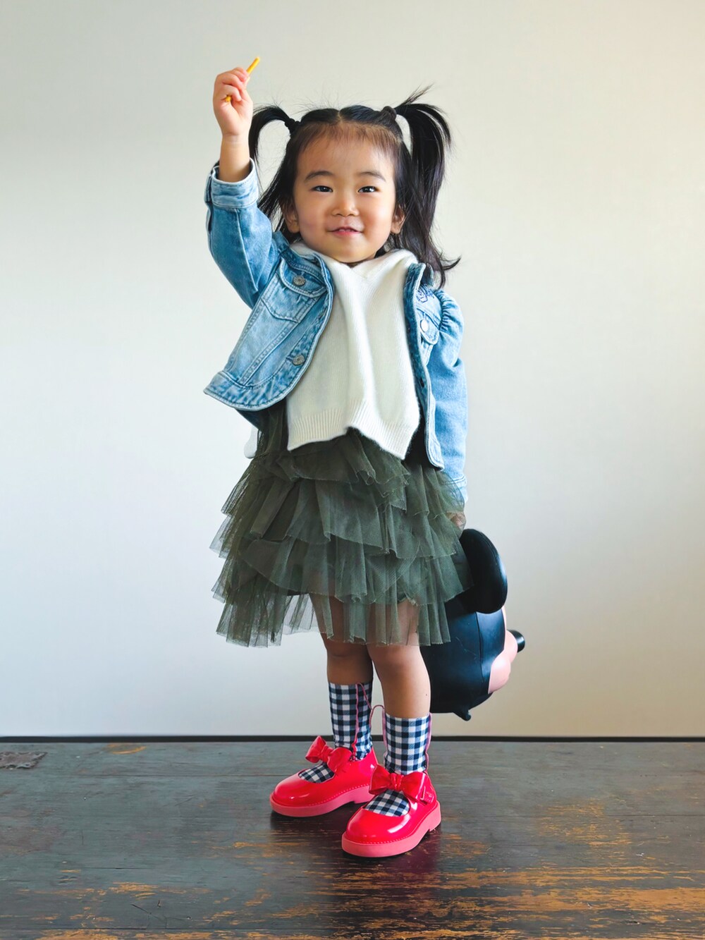 ブラック系のハンドバッグ、レッド系のドレスシューズ、ブルー系のデニムジャケットを着用したキッズの秋コーディネートの3枚目の写真