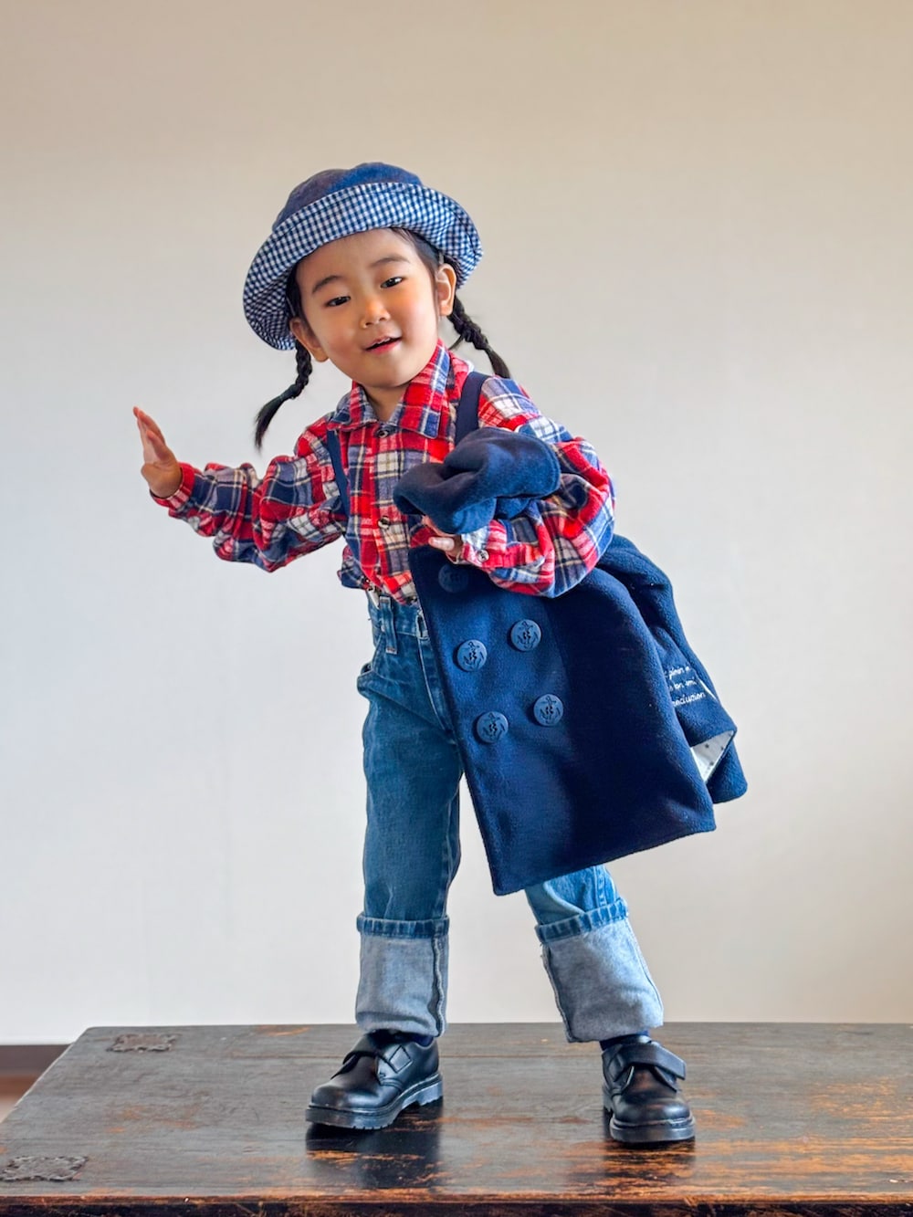 レッド系のシャツ/ブラウス、ブラック系のポンチョ、ブルー系のデニムパンツを着用したキッズの秋コーディネートの4枚目の写真