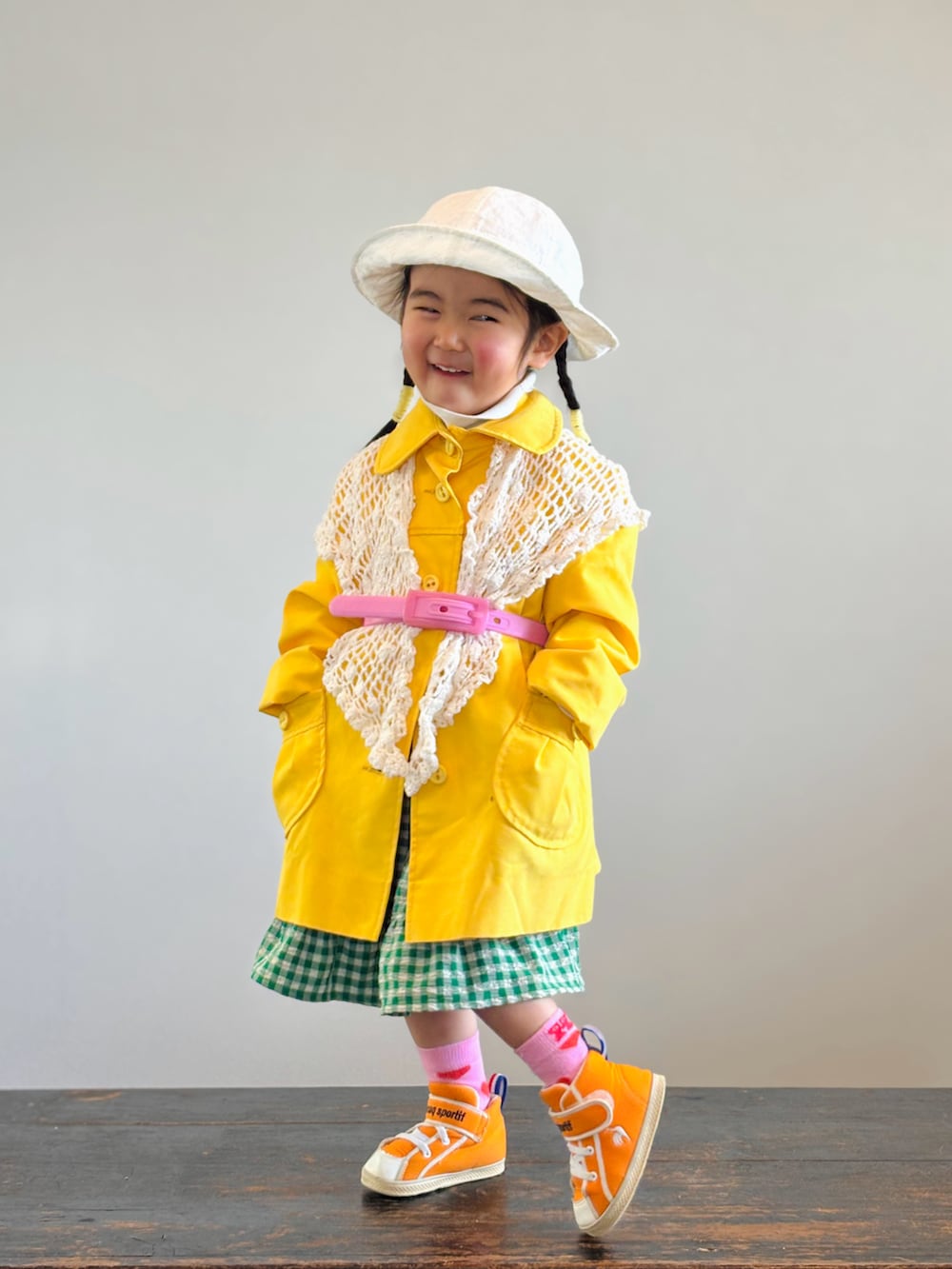 グリーン系のスカート、ホワイト系のTシャツ/カットソー、オレンジ系のスニーカーを着用したキッズの春コーディネートの3枚目の写真