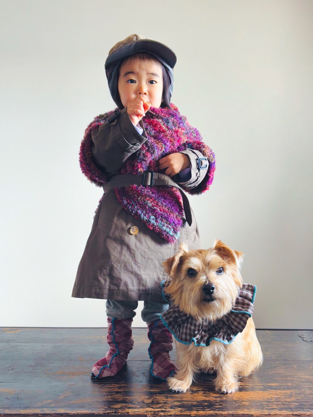 グリーン系のその他パンツ、パープル系のポンチョ、グリーン系のトレンチコートを着用したキッズの冬コーディネートの2枚目の写真