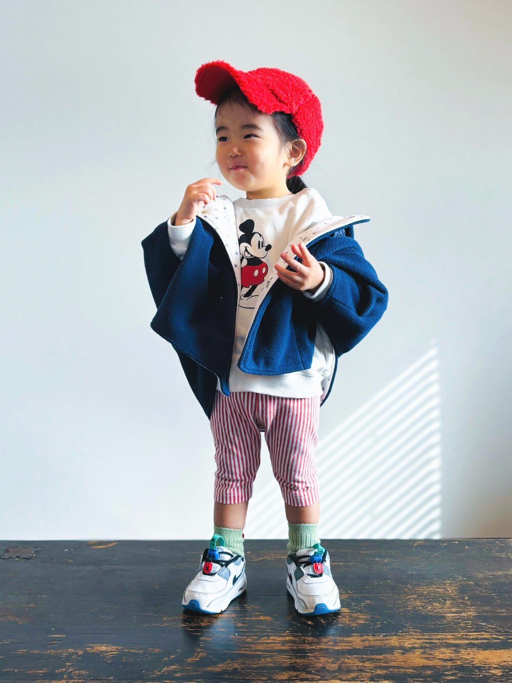 ホワイト系のスニーカー、レッド系のパンツ、ブラック系のポンチョを着用したキッズの冬コーディネートの2枚目の写真